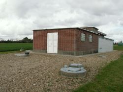 Kvong Vandværk - Lille rød bygning ved grusplads.