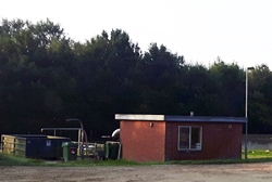 Lille bygning med en container ved siden af.