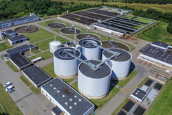 Luftfoto af Rens Vest med alle dets bygninger og tanke.