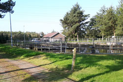 Spildevandstank med bygning i baggrunden.